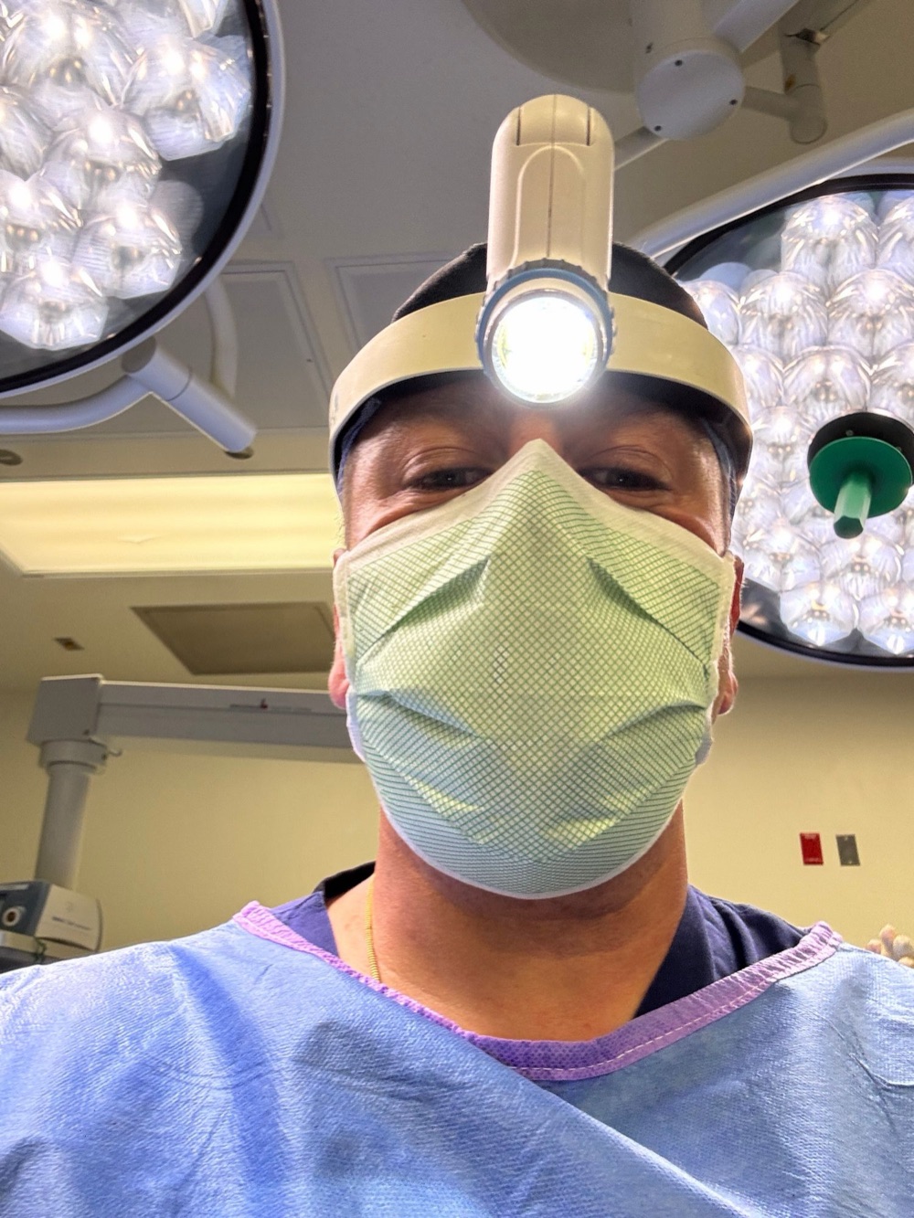 Dr. Nader Salib in surgical scrubs and headlight in a hospital operating room
